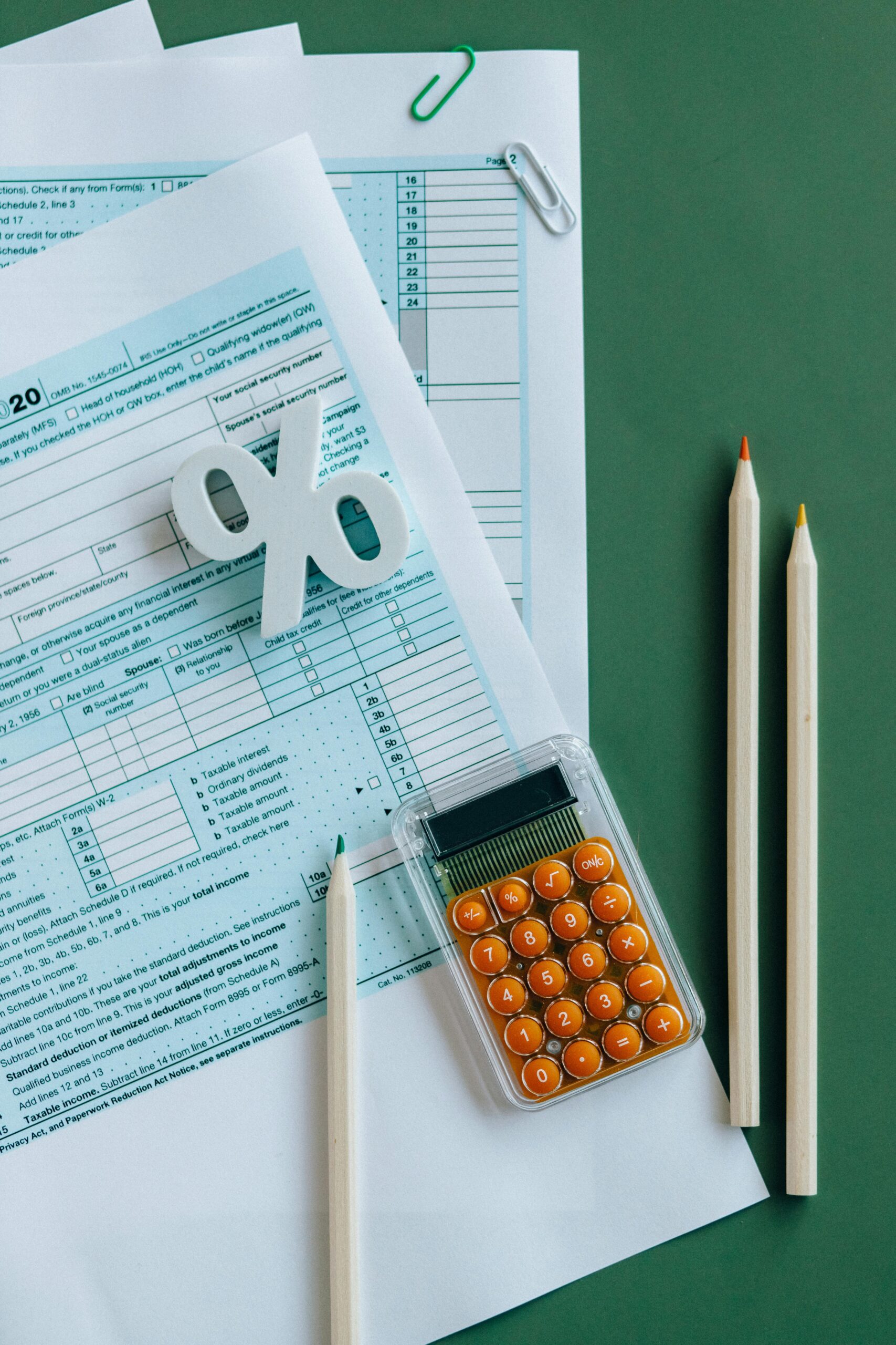 Why February Is the Right Time for Toronto & GTA Businesses to Get Tax-Ready Without the Panic Flat lay of tax documents, calculator, and pencils on green surface.